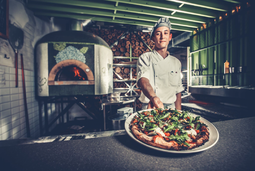 młody kucharz trzymający talerz z włoską pizzą